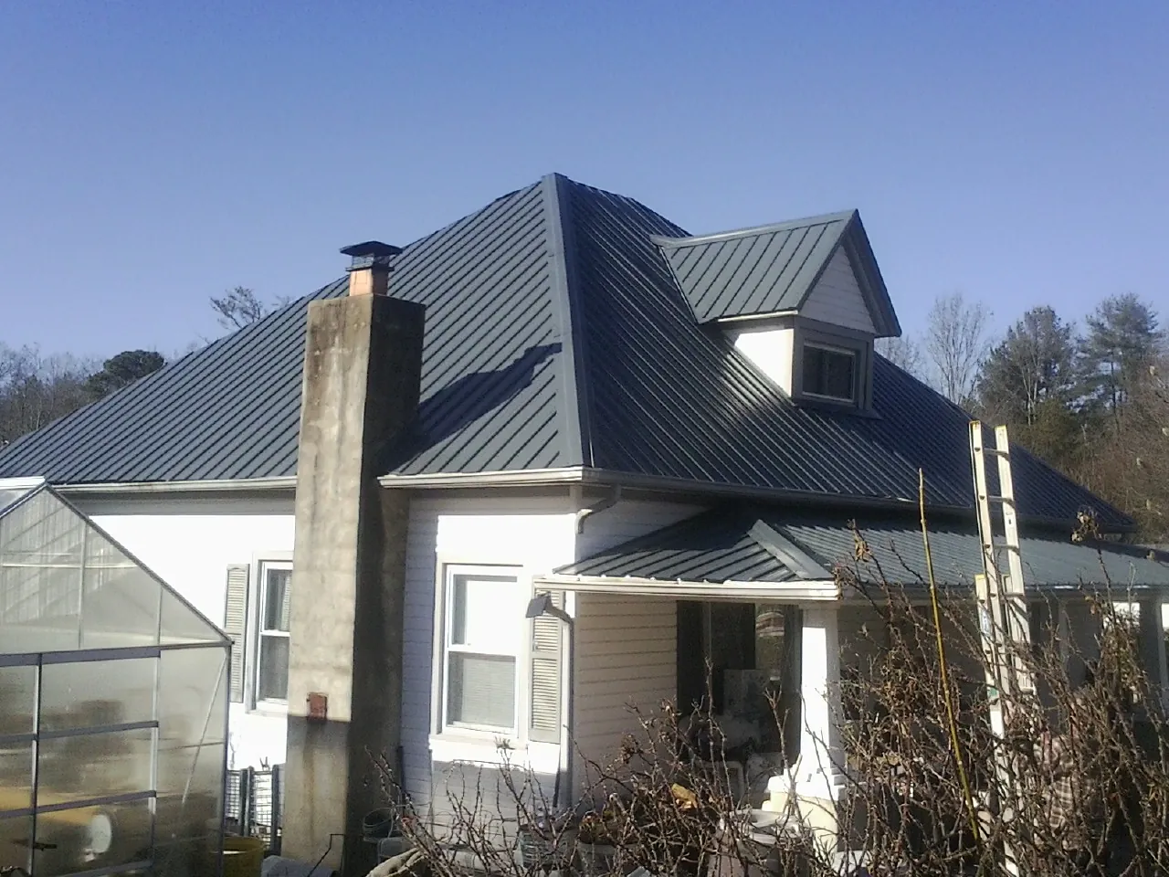 Dark blue standing seam metal roof on a white farmhouse with dormer — Slate & Tile Roof Repair by Roofing Brothers in Shipman