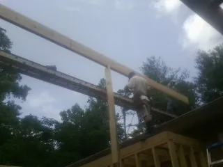 Carpenter setting a ridge beam over a new addition frame — Ice Dam Removal by Roofing Brothers in Shipman
