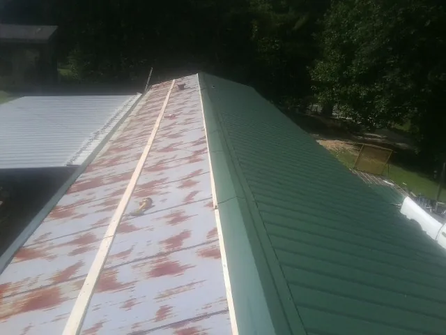 Old rusted panels beside newly installed green metal roofing — Wind Damage Roof Repair by Roofing Brothers in Shipman