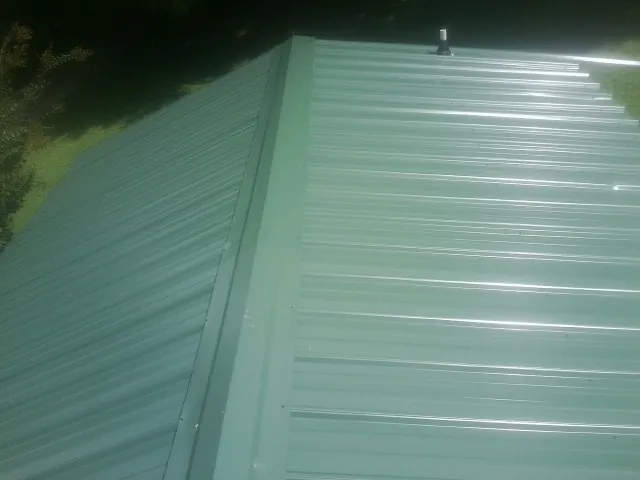 New green metal panels meeting at the ridge of a roof — Flat Roof Repair work by our crew in Shipman