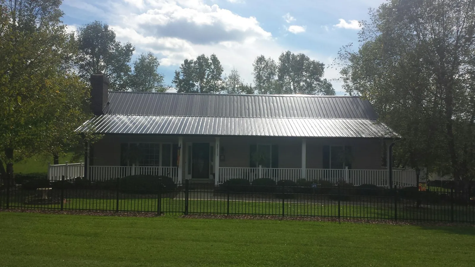 Gray metal roof on a brick ranch with a full width front porch — Gutter Guard Installation work by our crew in Shipman
