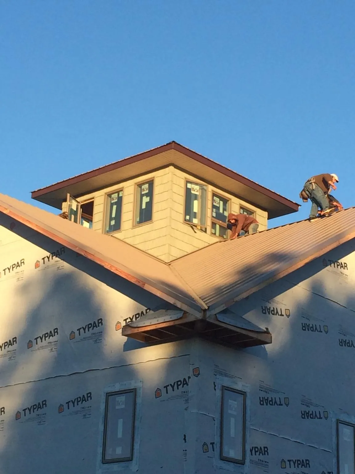 Roofers working around a rooftop cupola on a new metal roof at sunset — Roof Waterproofing in Shipman by Roofing Brothers
